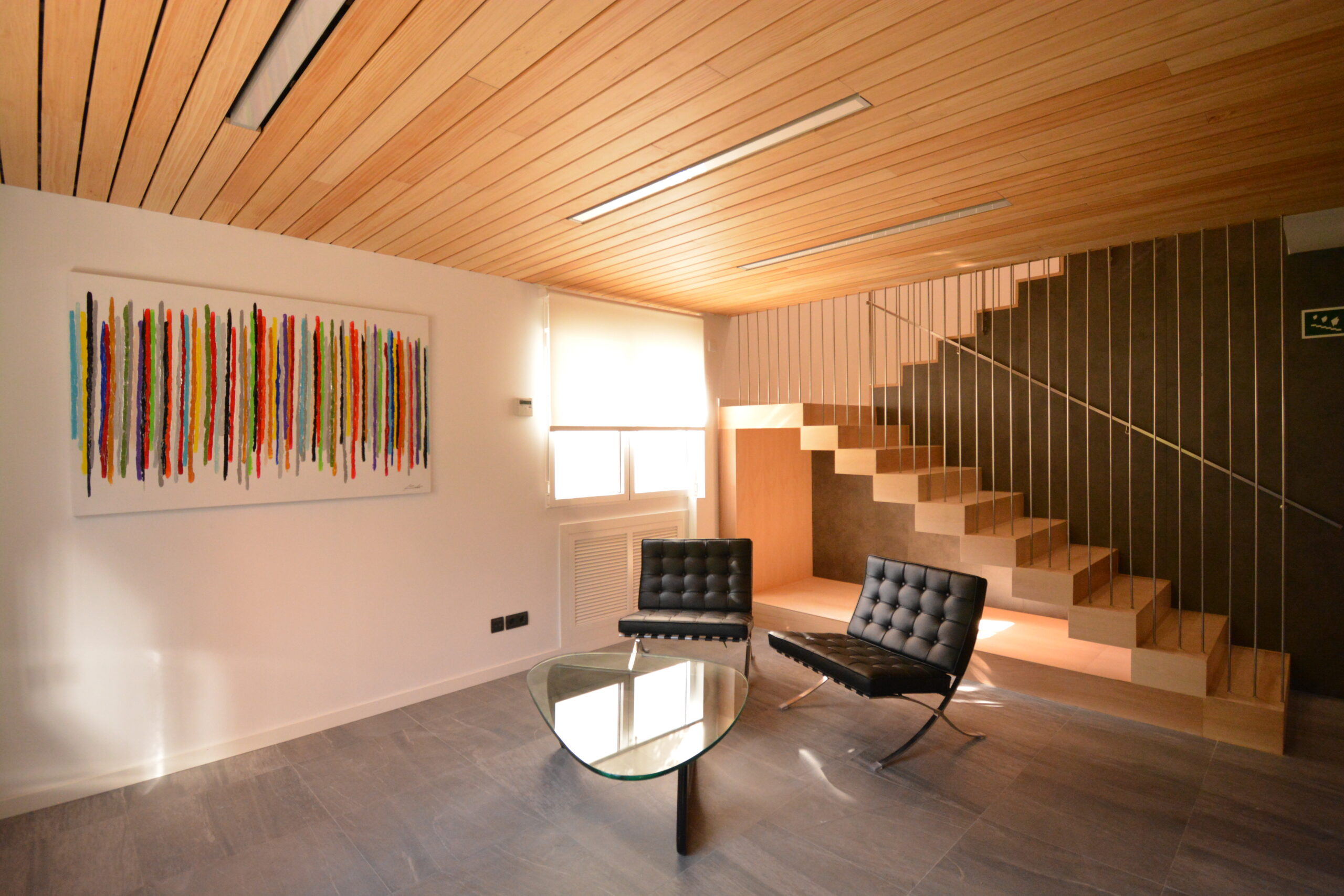 Espacio de espera Espacio de espera con asientos negros y una mesa central.